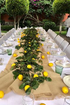 a long table with lemons and greenery on it