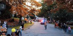 a group of people walking down a street next to a firetruck and halloween decorations