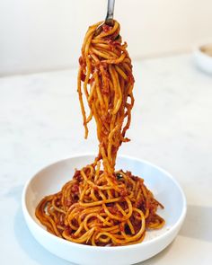 spaghetti being lifted from a white bowl