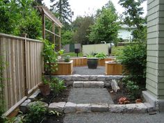 an outdoor garden with stone steps leading to a wooden fence and green trees in the background