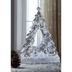 a clear christmas tree made out of ice and snow flakes on top of a table