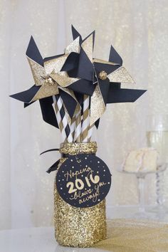 a vase filled with black and gold paper straws on top of a white table