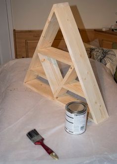 a paint can and brush sitting on top of a bed next to a wooden triangle