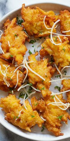 some fried food on a white plate with parmesan cheese