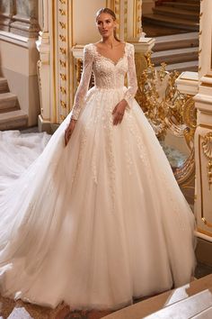 a woman in a white wedding dress standing next to a stair case with gold trimmings