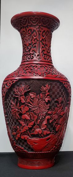 a red and black vase sitting on top of a white table