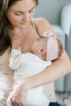 a woman holding a baby in her arms and looking down at it's breast