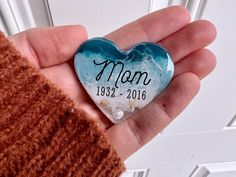 a hand holding a heart shaped glass ornament that reads mom 1932 - 2016