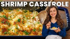 a woman holding a plate of food in front of a dish with shrimp casserole