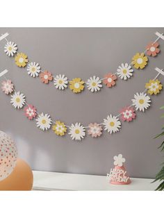 paper flowers are hanging on the wall next to a potted plant and cake topper