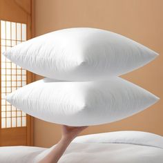 two white pillows sitting on top of a bed