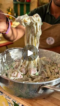 a man is holding a ladle full of noodles with meat and vegetables in it