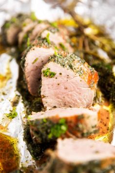 some meat is laying on tin foil covered in herbs and seasoning next to other food items