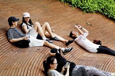 three people sitting on the ground with their legs crossed and one person holding a cell phone