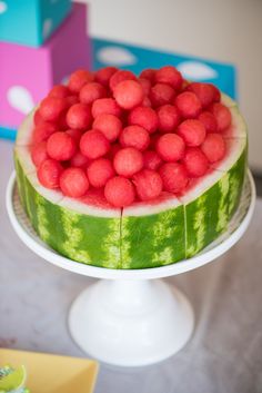 a watermelon and raspberry cake is displayed on a table with other items