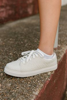 Elevate your outfit with our White Pearl Sneakers! These lace-up sneakers feature beaded pearls for a touch of sophistication. Not only stylish, they're also comfortable for all-day wear. Pair these versatile sneakers with so many different looks! runs true to size Spring Sneakers With Rhinestones, Casual Rhinestone Sneakers For Spring, Trendy Rhinestone Sneakers For Spring, Casual Sneakers With Rhinestones And Round Toe, Casual Low-top Sneakers With Rhinestones, Elegant Lace-up Sneakers For Spring, Elegant Low-top Sneakers With Laces, Elegant Synthetic Sneakers For Spring, Dressy Tennis Shoes