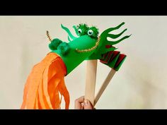 a person holding two wooden sticks with an octopus puppet on it's head and mouth