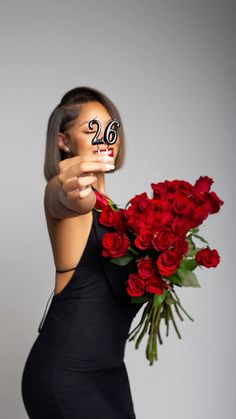 a woman holding a bouquet of red roses in front of her face with the number twenty on it