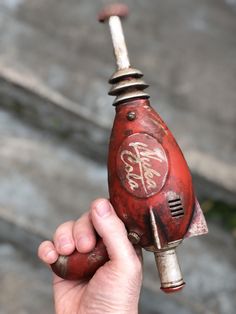 a hand holding an old red object with writing on it