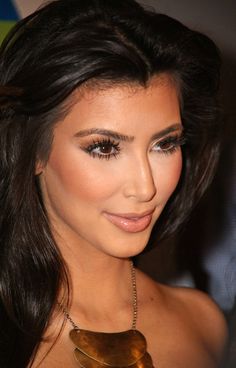 a close up of a woman with long hair and brown eyeshadow wearing a gold necklace