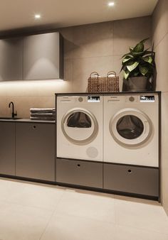 a washer and dryer in a very modern style home laundry room with grey cabinets