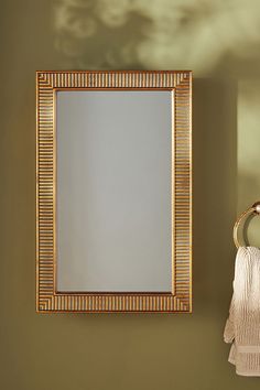 a bathroom mirror sitting on top of a wall next to a towel rack