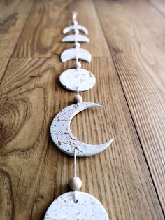 three white moon and crescent hangings on a wooden floor with beads attached to them