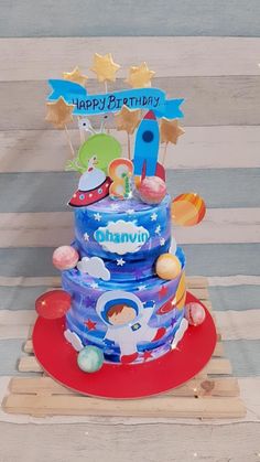 a birthday cake with an outer space theme on the top and happy birthday sign above it