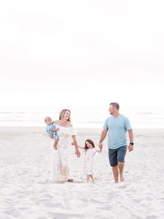 a family walking on the beach holding hands