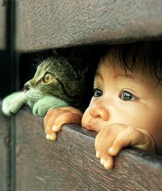 a small child is peeking out from behind a wall with a cat looking at him