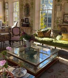 a living room filled with lots of furniture and flowers on top of a glass table