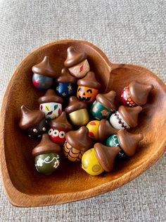 a wooden heart shaped bowl filled with lots of candy