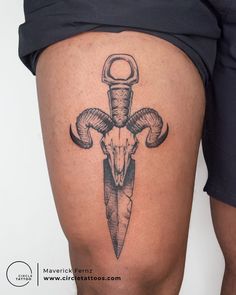 a tattoo on the leg of a person with a knife and ram skull in it