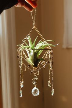 a person holding a plant in their hand with beads hanging from it's center