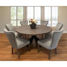 a dining room table with blue chairs and a vase full of flowers on the top