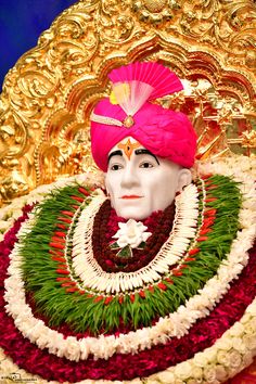 an idol is displayed in front of a gold plated backdrop with red, white and green garlands