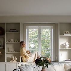 a woman sitting on top of a couch next to a window