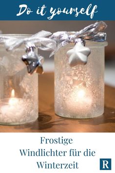 two glass jars filled with candles on top of a table