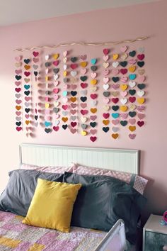 a bedroom with pink walls and lots of hearts hanging on the wall above the bed