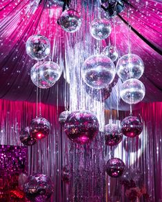 disco ball chandelier hanging from the ceiling in front of pink curtained backdrop