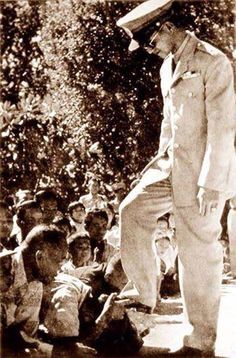 an old black and white photo of a man standing in front of a group of people