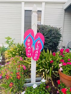 two pink flip flops sitting on top of a white pole in front of flowers