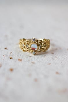 Sonia Moonstone Floral Gold Lace Filigree 18K Gold Vermeil Ring features moonstone in the centre, accented by lace filigree on the sides. It is similar to Monique Moonstone Ring in our shop, but the details of the ring are different. This is an adjustable ring, it comes in one size only and fits US ring size 5 to 8. ◊ 18K Gold Vermeil ◊ Adjustable Ring ◊ Sold in ONE SIZE only ◊ Fits US ring size 5 to 8 ◊ Lab Moonstone and cubic zircons ◊ Delivered in our signature royal blue box, it makes the pe Heirloom Gold Opal Promise Ring, Ethereal Gold Moonstone Ring For Gift, Ethereal Gold Moonstone Ring Gift, Gold Moonstone Ring As Gift, Gold Moonstone Open Ring For Anniversary, Gold Open Ring Moonstone For Anniversary, Gold Moonstone Ring For Gift, Gold Open Moonstone Ring For Anniversary, 14k Gold Moonstone Ring With Gemstone Accents