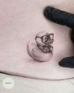 a small tattoo on the stomach of a person with glasses and a camera in his hand