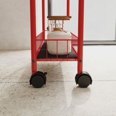 a red cart with a white object in it's center on top of a tile floor