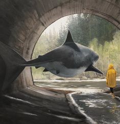 a person in yellow jacket looking at a shark through a tunnel with trees and water