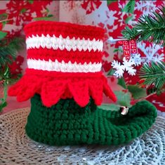 there is a crocheted christmas hat on top of a green boot with red and white stripes