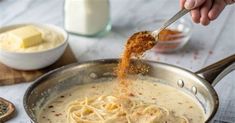 a person is stirring some food in a pan on the table next to other ingredients