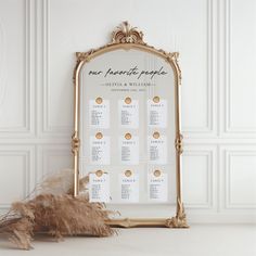 a wedding seating chart on a gold framed mirror next to dried flowers and dry grass