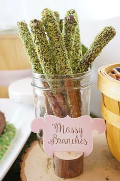 there is a jar full of mossy branches next to a basket with rocks in it